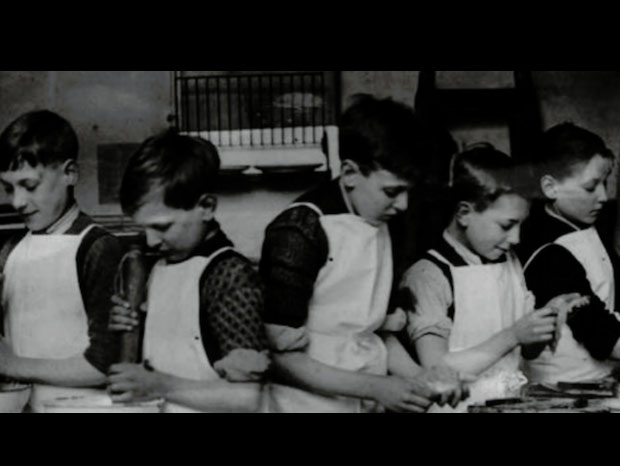 A vintage black and white photo of young kids in aprons